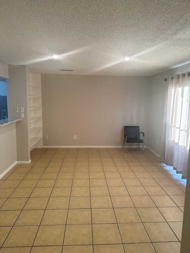 tiled spare room featuring a textured ceiling