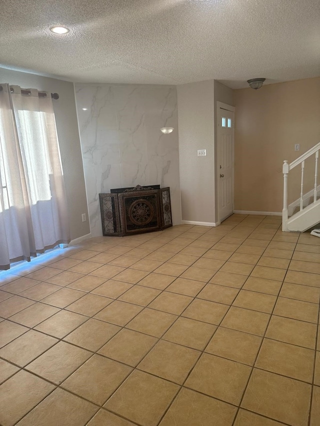 unfurnished living room with a fireplace, light tile patterned floors, and a textured ceiling