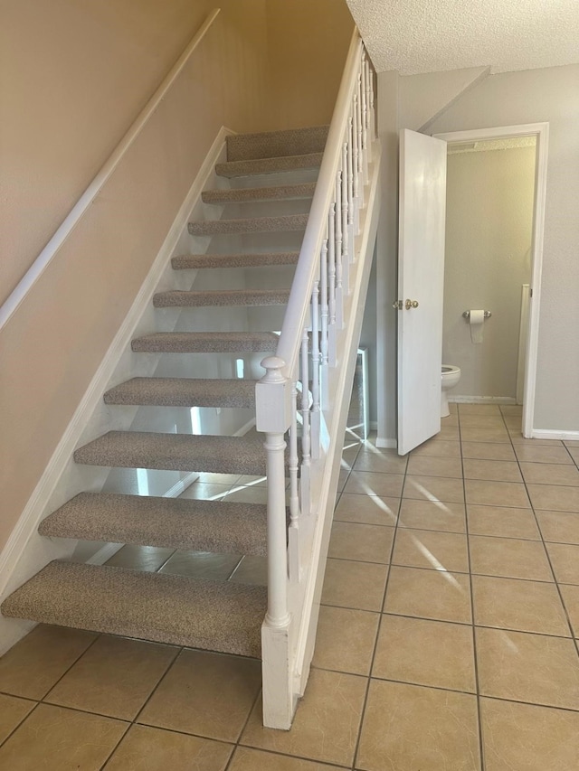 stairs with tile patterned floors and a textured ceiling