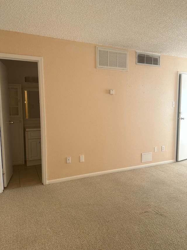 unfurnished room with carpet and a textured ceiling