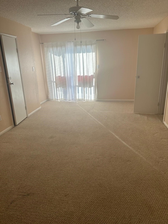 empty room with carpet, ceiling fan, and a textured ceiling