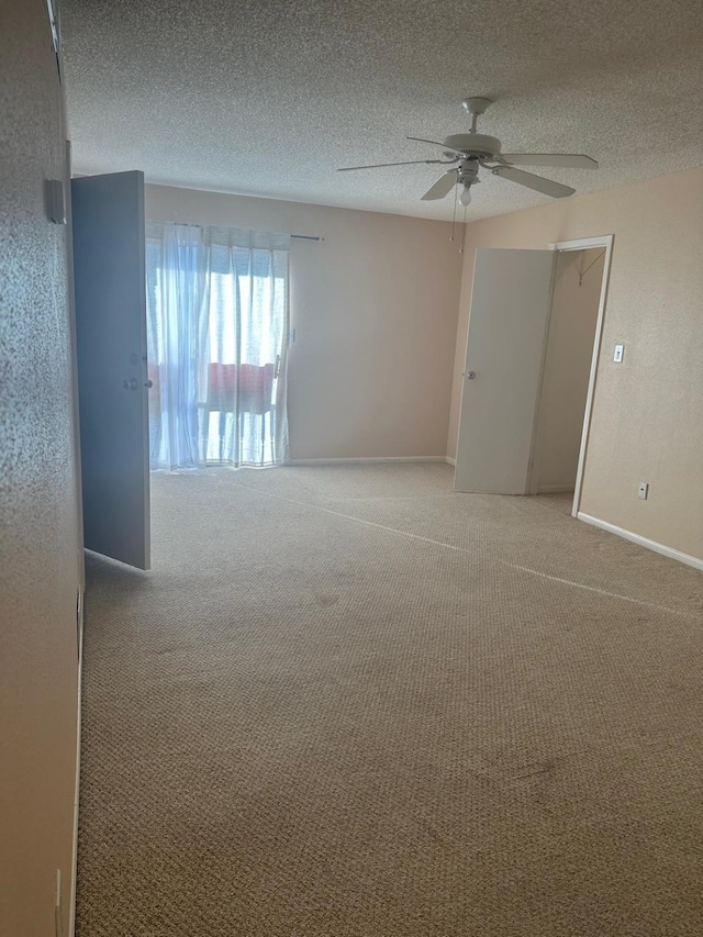 carpeted empty room with ceiling fan and a textured ceiling