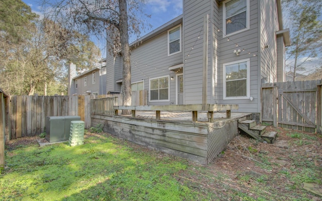 rear view of property featuring a lawn and a deck