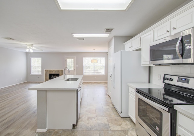 kitchen featuring appliances with stainless steel finishes, a kitchen island with sink, ceiling fan, sink, and white cabinets