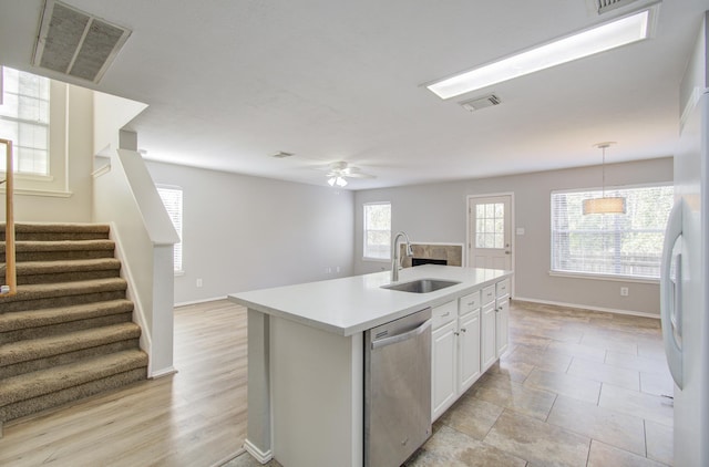 kitchen featuring stainless steel dishwasher, sink, decorative light fixtures, a center island with sink, and white cabinets