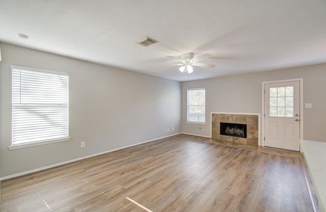 unfurnished living room featuring ceiling fan, a fireplace, and light wood-type flooring