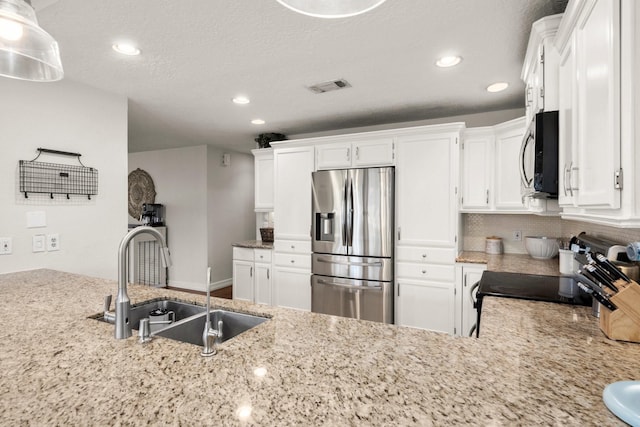 kitchen with pendant lighting, stove, sink, stainless steel fridge with ice dispenser, and white cabinetry