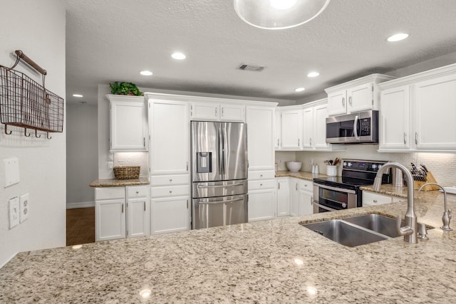 kitchen featuring a textured ceiling, white cabinetry, sink, and appliances with stainless steel finishes