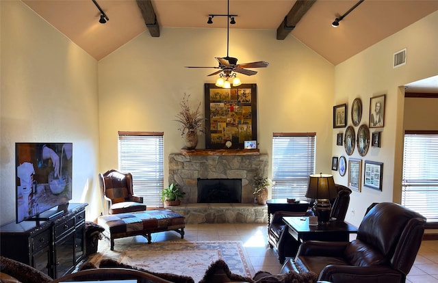 living room featuring ceiling fan, rail lighting, beamed ceiling, a fireplace, and light tile patterned floors