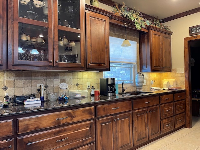 kitchen with tasteful backsplash, light tile patterned flooring, dark stone counters, and ornamental molding