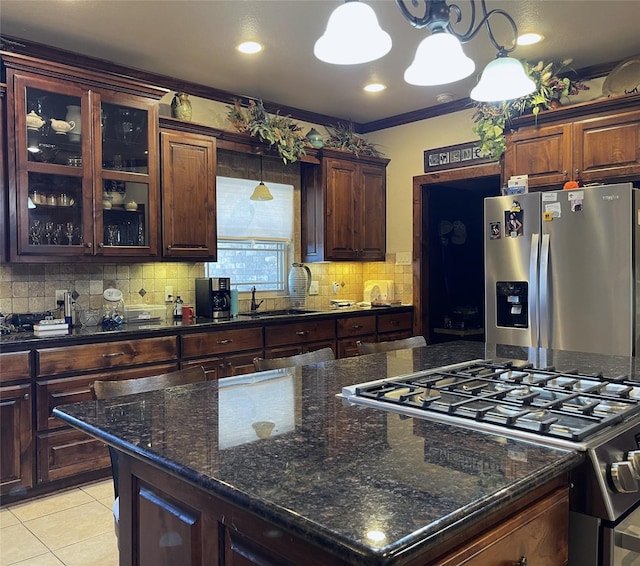 kitchen with ornamental molding, dark brown cabinets, stainless steel appliances, light tile patterned floors, and hanging light fixtures