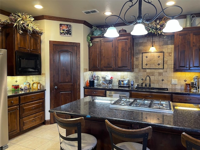 kitchen with sink, stainless steel appliances, tasteful backsplash, decorative light fixtures, and a kitchen bar