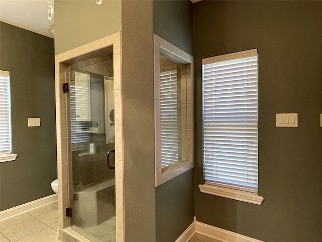 bathroom with tile patterned flooring, toilet, and an enclosed shower