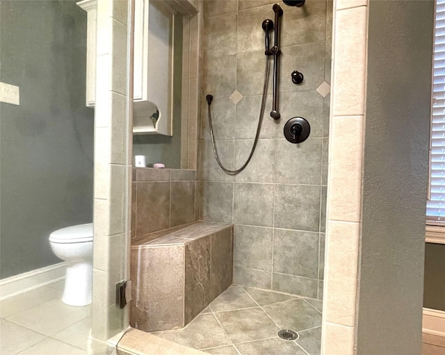 bathroom with toilet, a tile shower, and tile patterned floors