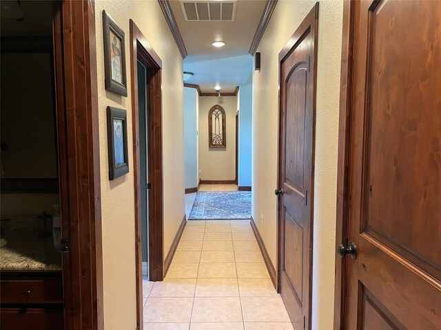 corridor featuring light tile patterned floors and crown molding