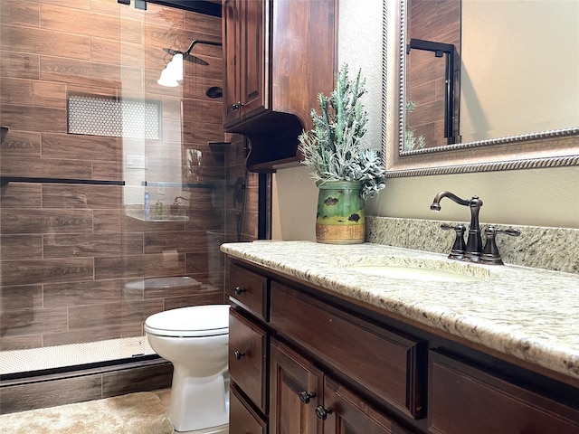 bathroom featuring a tile shower, vanity, and toilet