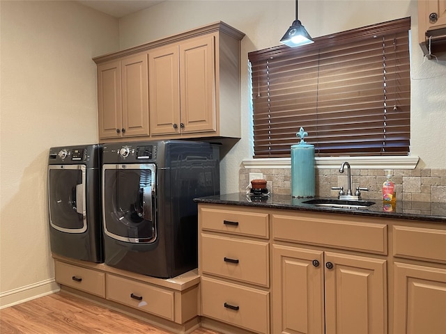 laundry room with cabinets, light hardwood / wood-style flooring, washer and clothes dryer, and sink