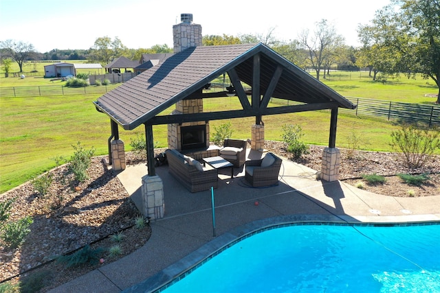 view of pool with a lawn, an outdoor living space with a fireplace, a gazebo, a rural view, and a patio