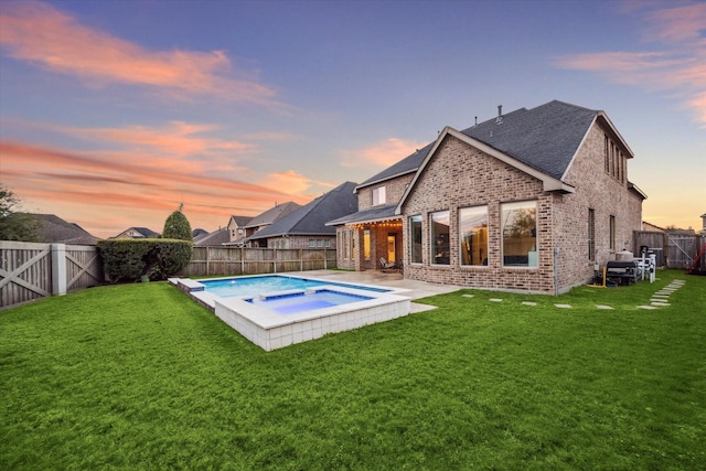 back of house at dusk with a patio area, a fenced backyard, a lawn, and brick siding