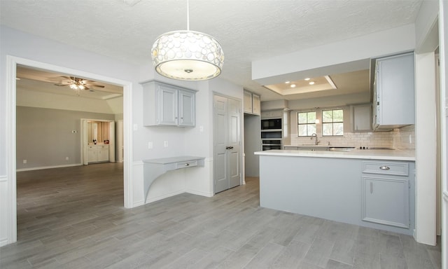 kitchen with sink, ceiling fan, tasteful backsplash, kitchen peninsula, and black microwave