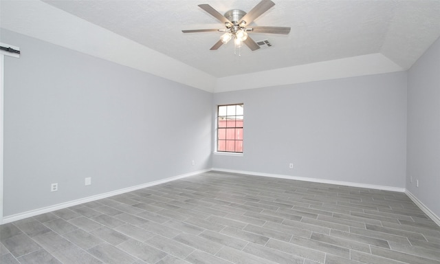 spare room featuring a tray ceiling, ceiling fan, and a textured ceiling