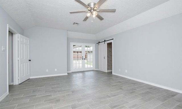 unfurnished room featuring french doors, a barn door, a textured ceiling, and ceiling fan