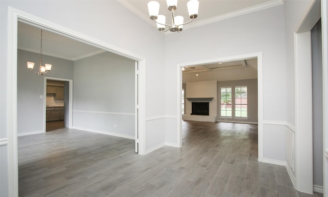 interior space with a fireplace, wood-type flooring, an inviting chandelier, and crown molding