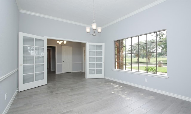 unfurnished room featuring a notable chandelier, crown molding, and french doors