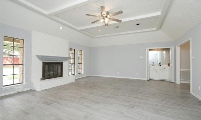 unfurnished living room with ceiling fan, light wood-type flooring, and a brick fireplace