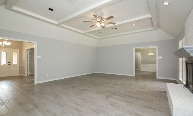 unfurnished living room with ceiling fan with notable chandelier, a textured ceiling, and light hardwood / wood-style flooring