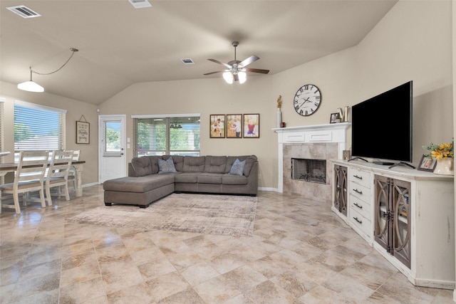 living room with vaulted ceiling, ceiling fan, a healthy amount of sunlight, and a tiled fireplace