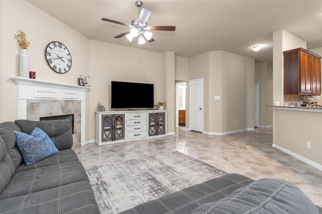 living room with a high end fireplace and ceiling fan