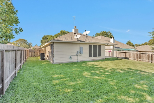 rear view of house featuring a lawn and central AC unit