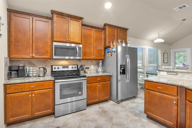 kitchen featuring light stone countertops, appliances with stainless steel finishes, backsplash, and vaulted ceiling