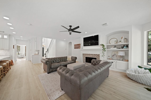 living room with light hardwood / wood-style flooring, built in features, and ceiling fan