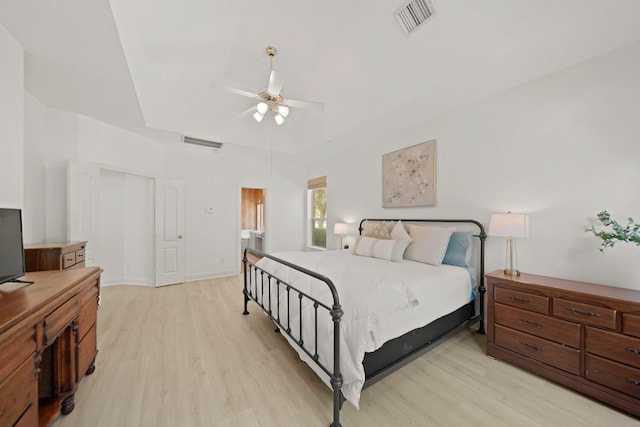 bedroom with a tray ceiling, light hardwood / wood-style floors, and ceiling fan