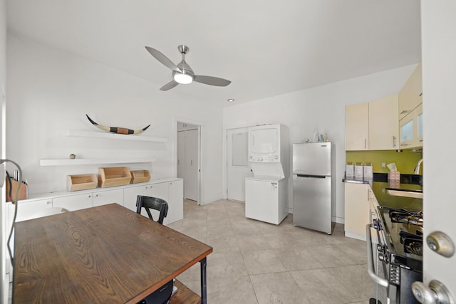 kitchen featuring appliances with stainless steel finishes, sink, stacked washer and clothes dryer, light tile patterned floors, and ceiling fan