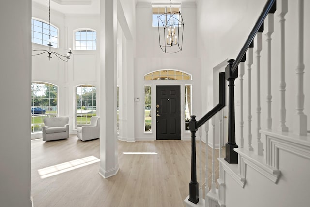 foyer entrance featuring ornamental molding, a wealth of natural light, light hardwood / wood-style floors, and a chandelier