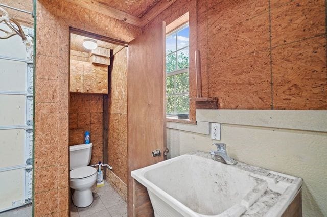 bathroom with tile patterned floors, toilet, sink, and a washtub