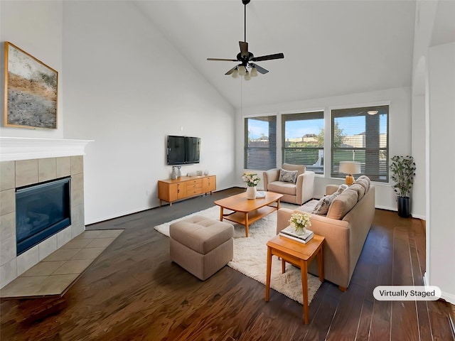 living room with a tiled fireplace, ceiling fan, high vaulted ceiling, and dark hardwood / wood-style floors