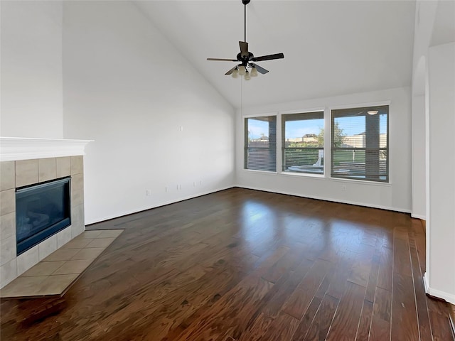 unfurnished living room with a tile fireplace, high vaulted ceiling, ceiling fan, and dark wood-type flooring