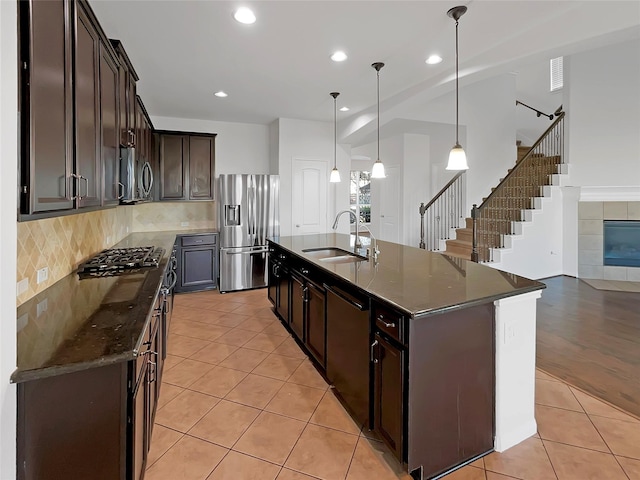 kitchen with sink, stainless steel appliances, pendant lighting, a kitchen island with sink, and light tile patterned floors