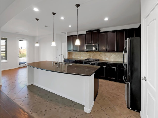 kitchen featuring pendant lighting, a kitchen island with sink, sink, light tile patterned floors, and appliances with stainless steel finishes