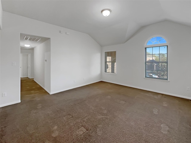 spare room featuring dark carpet and vaulted ceiling