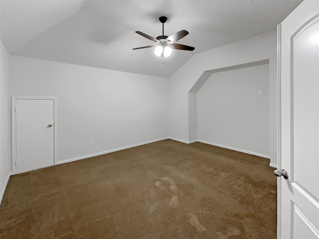 bonus room with ceiling fan, dark carpet, and vaulted ceiling