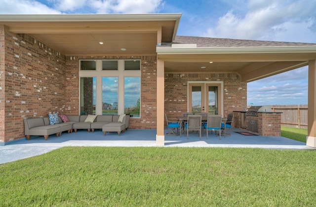 back of house featuring a lawn, an outdoor living space, exterior kitchen, and a patio