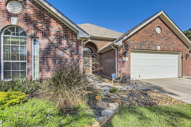 view of front of house featuring a garage, brick siding, driveway, and a shingled roof