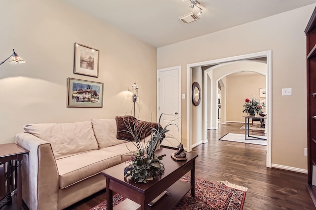 living area featuring dark wood-style floors, baseboards, visible vents, and arched walkways