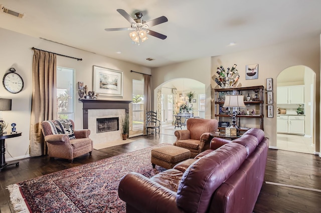 living room with visible vents, a premium fireplace, arched walkways, and wood-type flooring