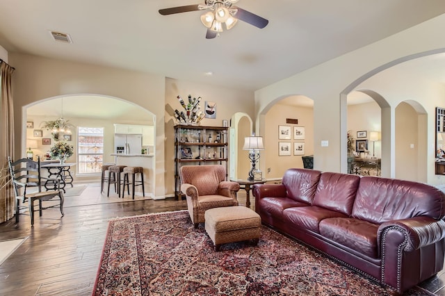 living area with visible vents, dark wood finished floors, baseboards, and ceiling fan